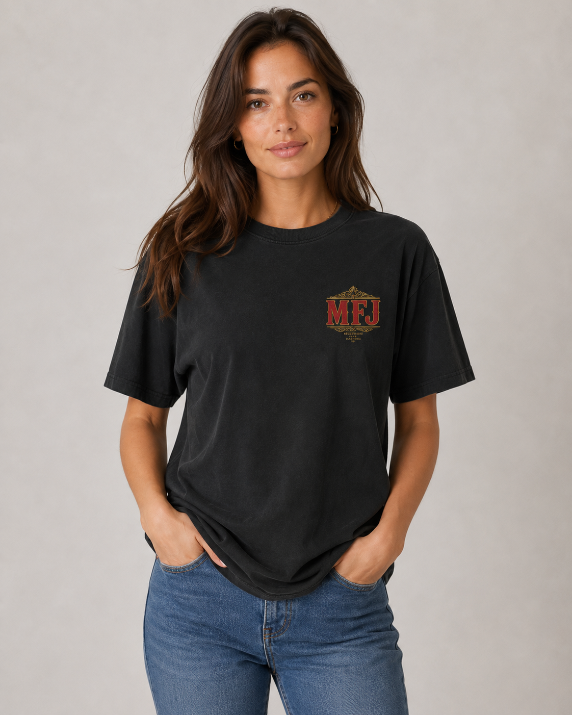 Female model wearing a black MFJ Theatre Critics heavyweight garment-dyed tee, showing the small MFJ left-chest graphic